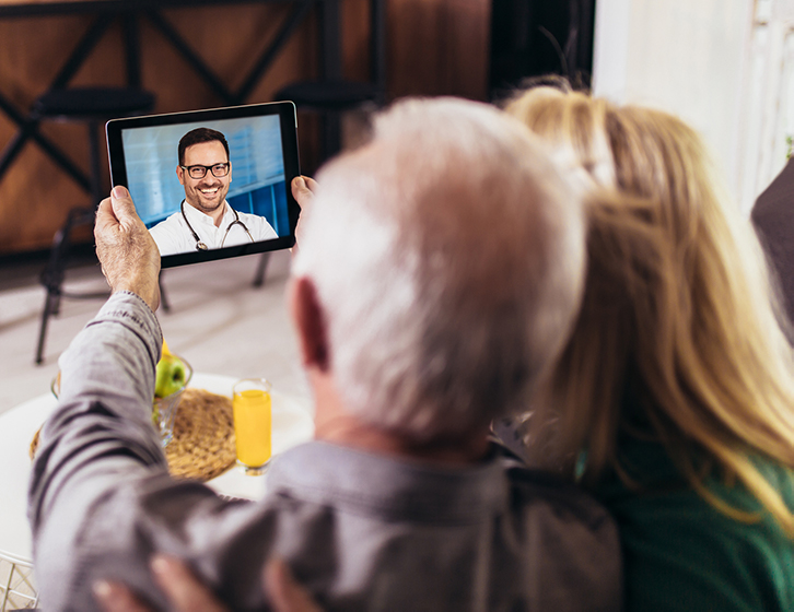 an elderly gentleman and lady holding tablet for a virtual visit