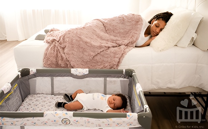 mom sleeping next to baby in crib