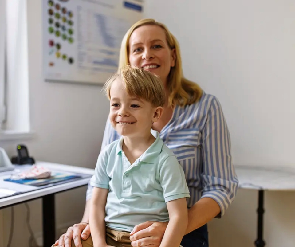 Mother with her son on her lap, both smiling and looking forward